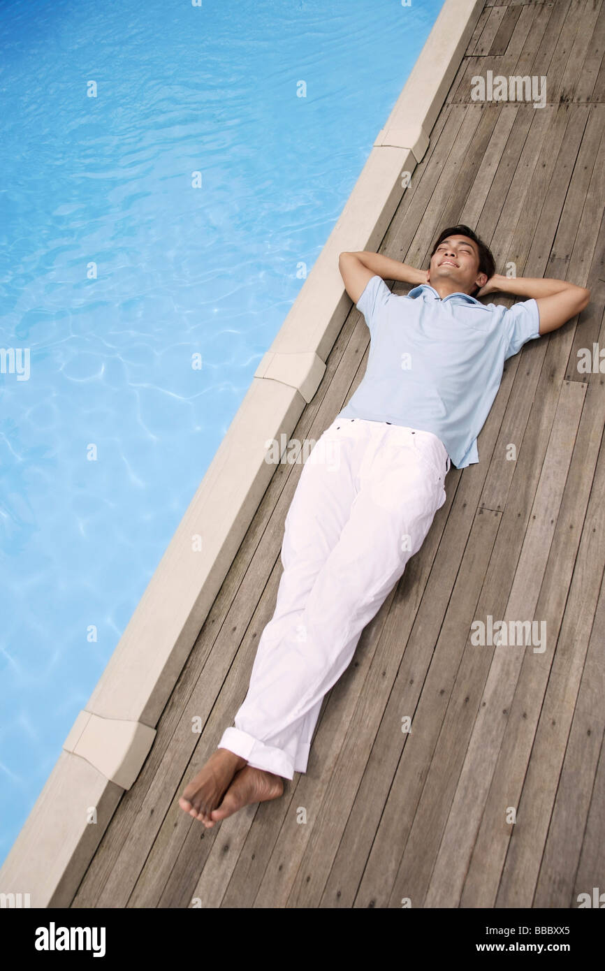 Man reclining by pool Stock Photo - Alamy