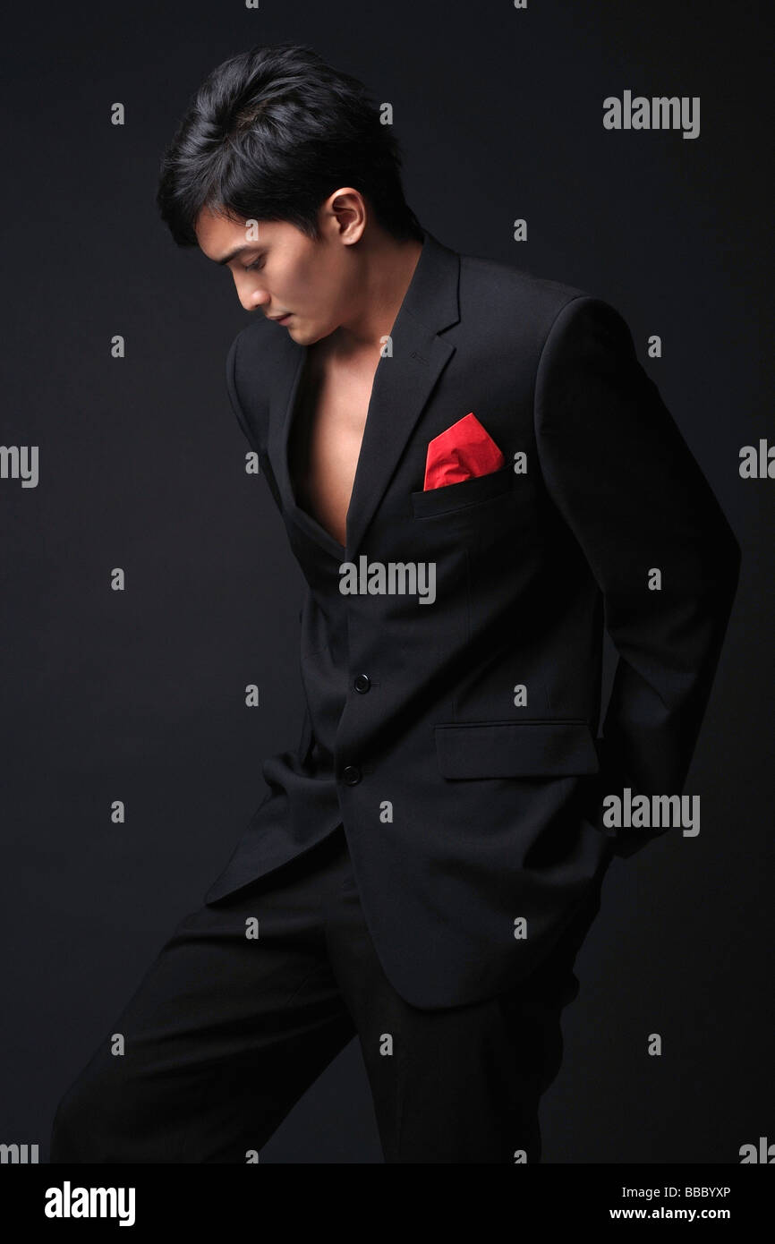 Young man in black suit looking down Stock Photo - Alamy