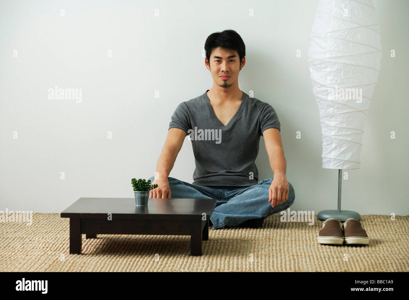 Young man sitting on floor, looking at camera Stock Photo - Alamy
