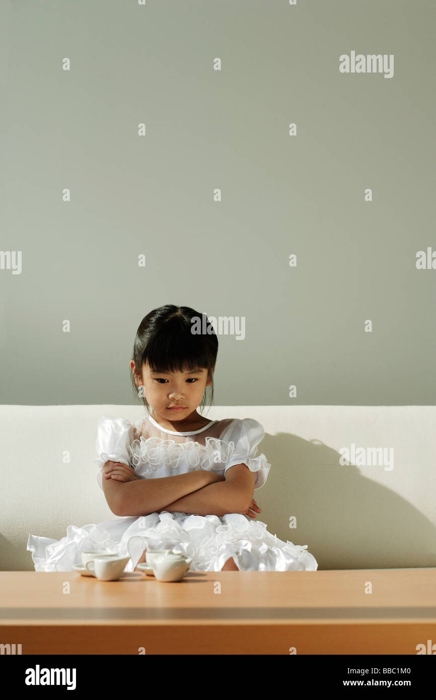 Girl sitting on sofa with tea set on coffee table Stock Photo - Alamy