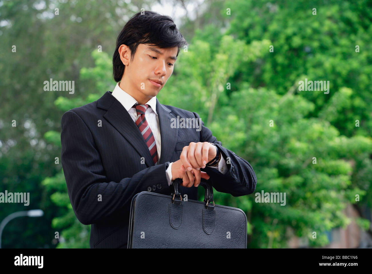 A man in a suit checks his watch for the time Stock Photo - Alamy