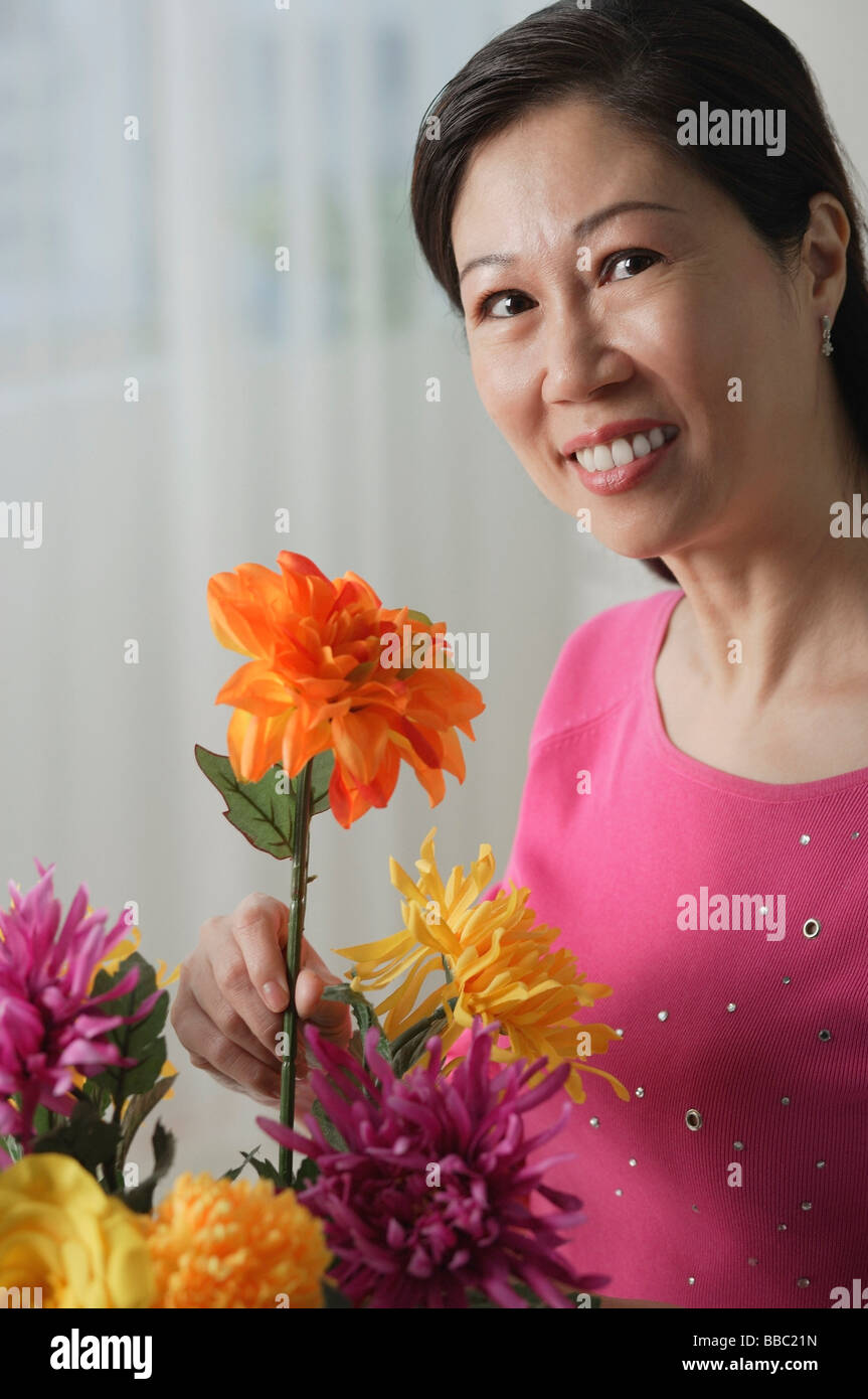Mature woman holding flowers, smiling at camera, portrait Stock Photo ...