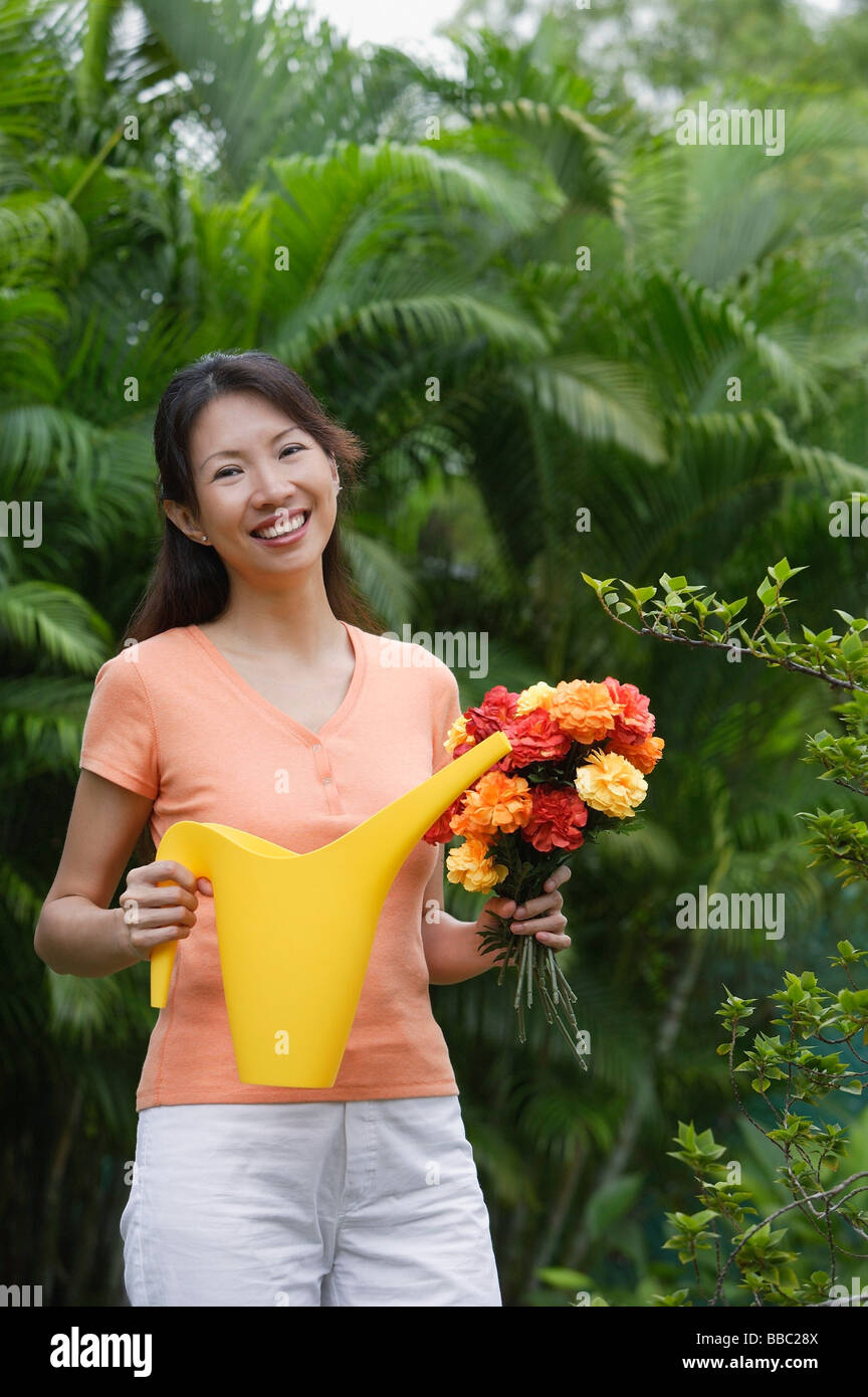 Woman in garden, holding bouquet of flowers and watering can Stock ...