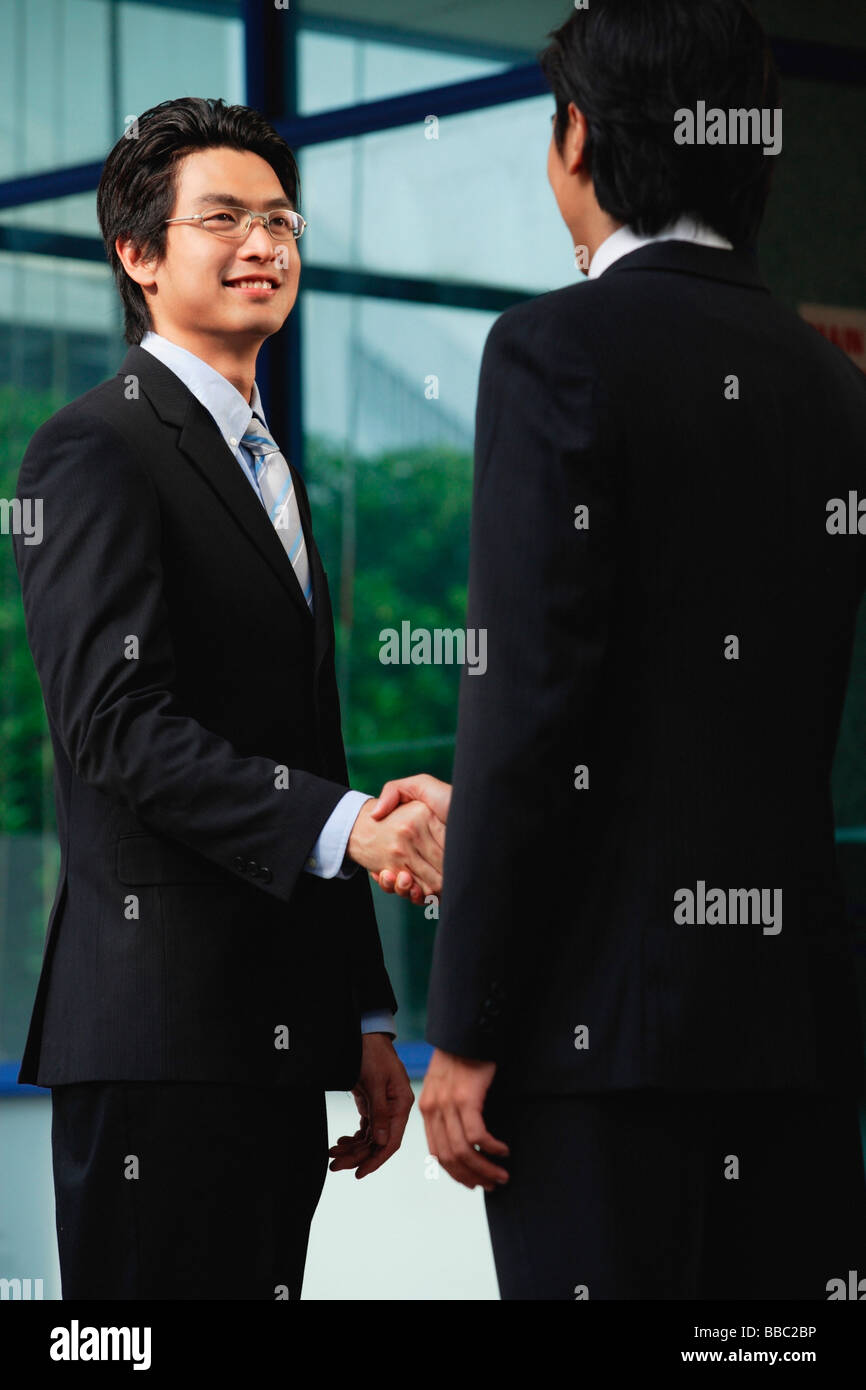 Two men wearing suits shake hands Stock Photo Alamy