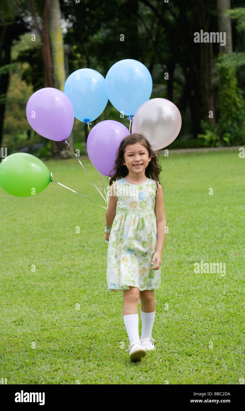 Girl walking on grass, holding a bunch of balloons Stock Photo - Alamy