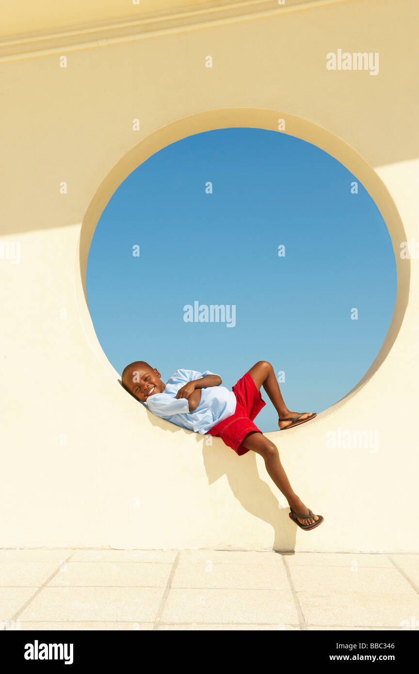 Young boy lying in circular window Stock Photo