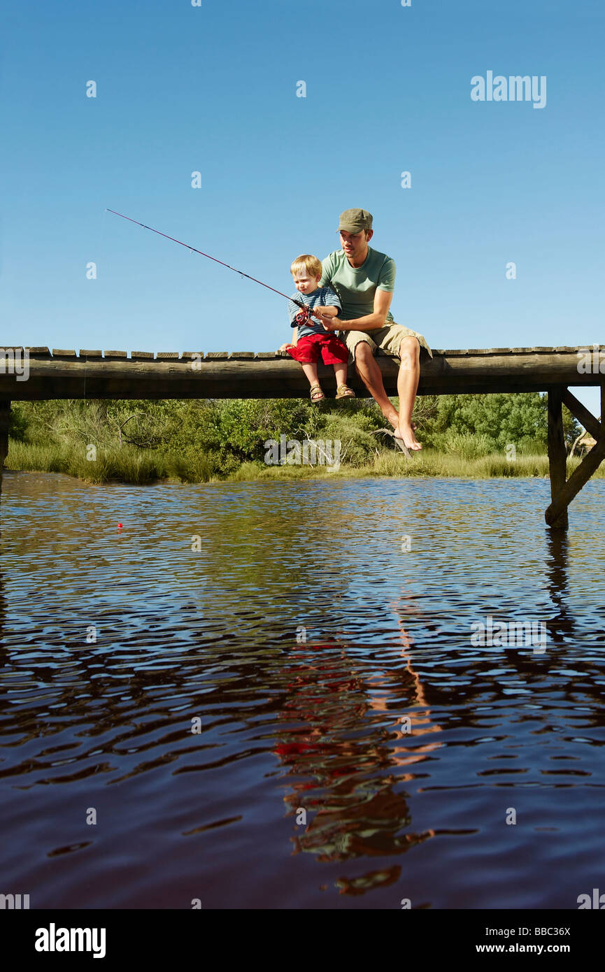 Father and son fishing from jetty Stock Photo