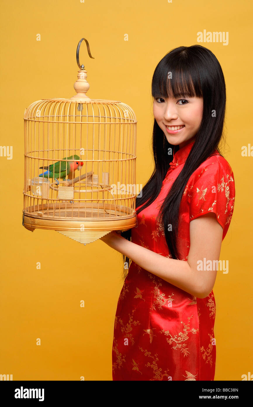 Young woman holding lovebird in bird cage, smiling Stock Photo