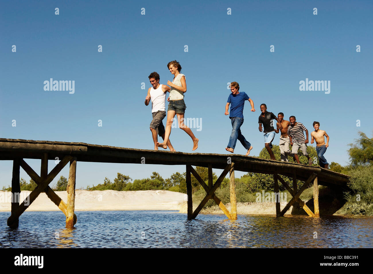 Group of teenagers running across jetty Stock Photo