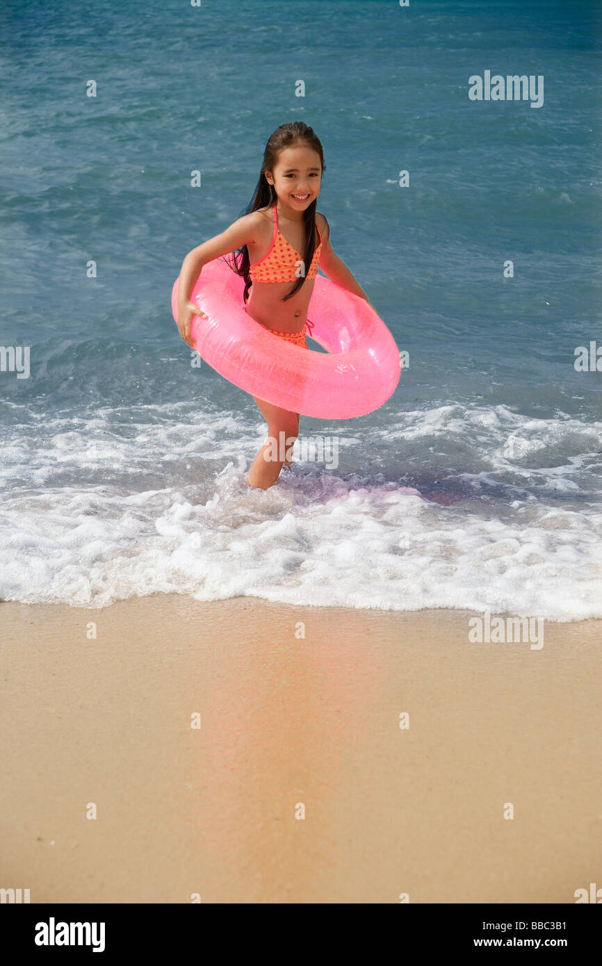 Young girl on beach carrying pink float around waist Stock Photo - Alamy
