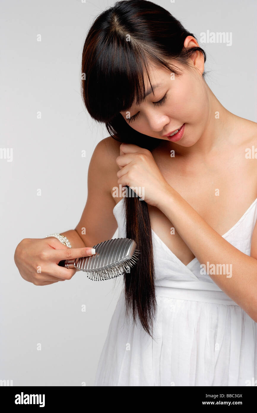 Young woman wearing white dress and brushing hair Stock Photo