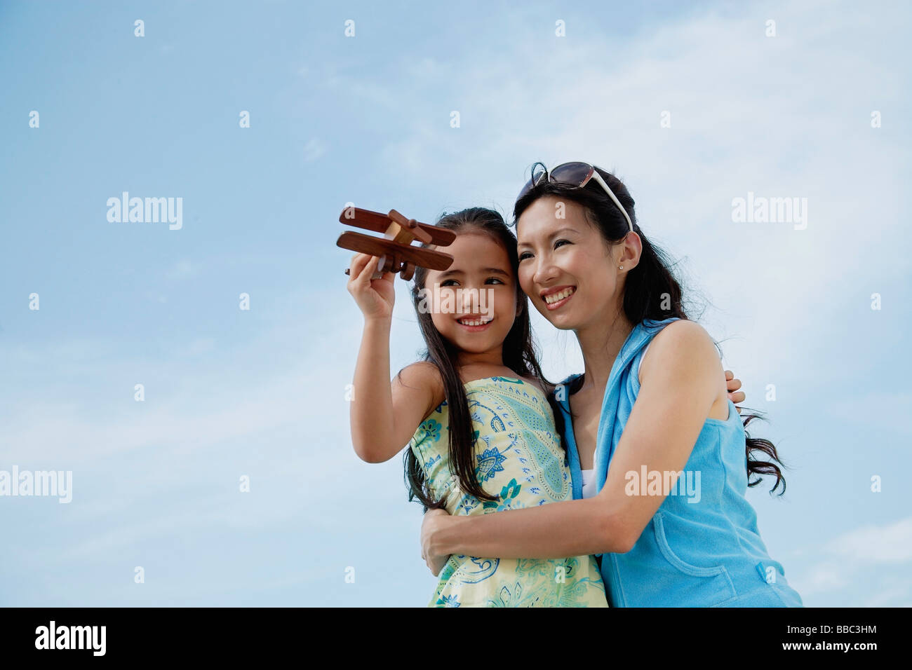 Mother and daughter flying wooden airplane, mother holding daughter Stock Photo