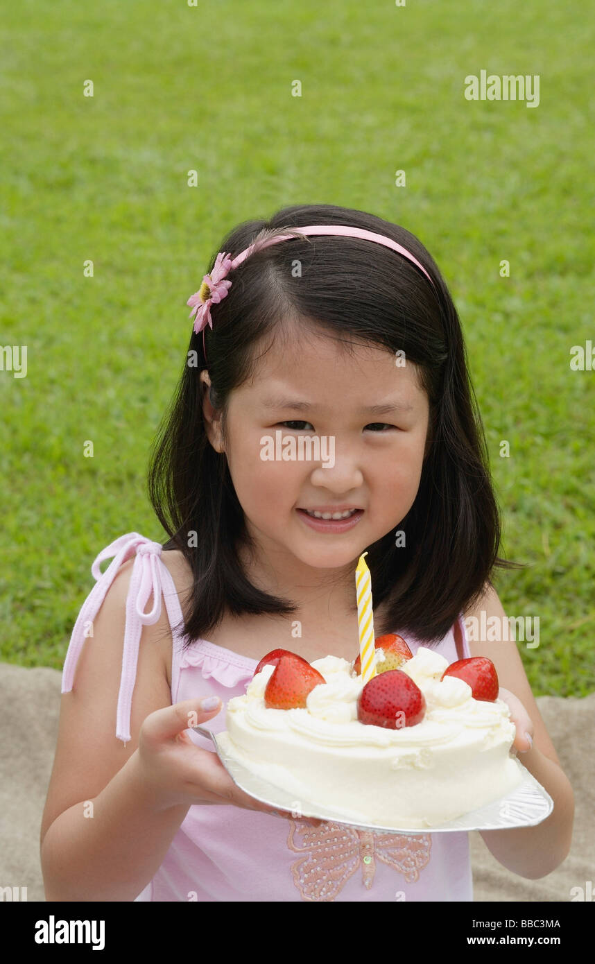 Girl holding birthday cake with one candle Stock Photo - Alamy