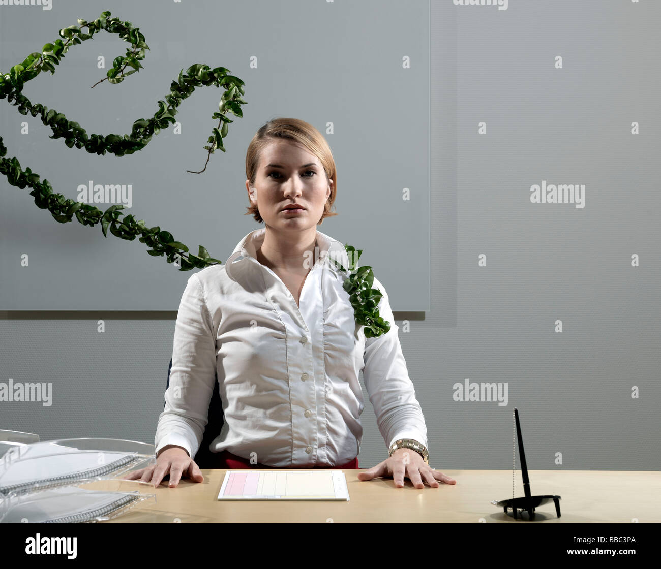 Woman by desk beeing attacked by plants Stock Photo