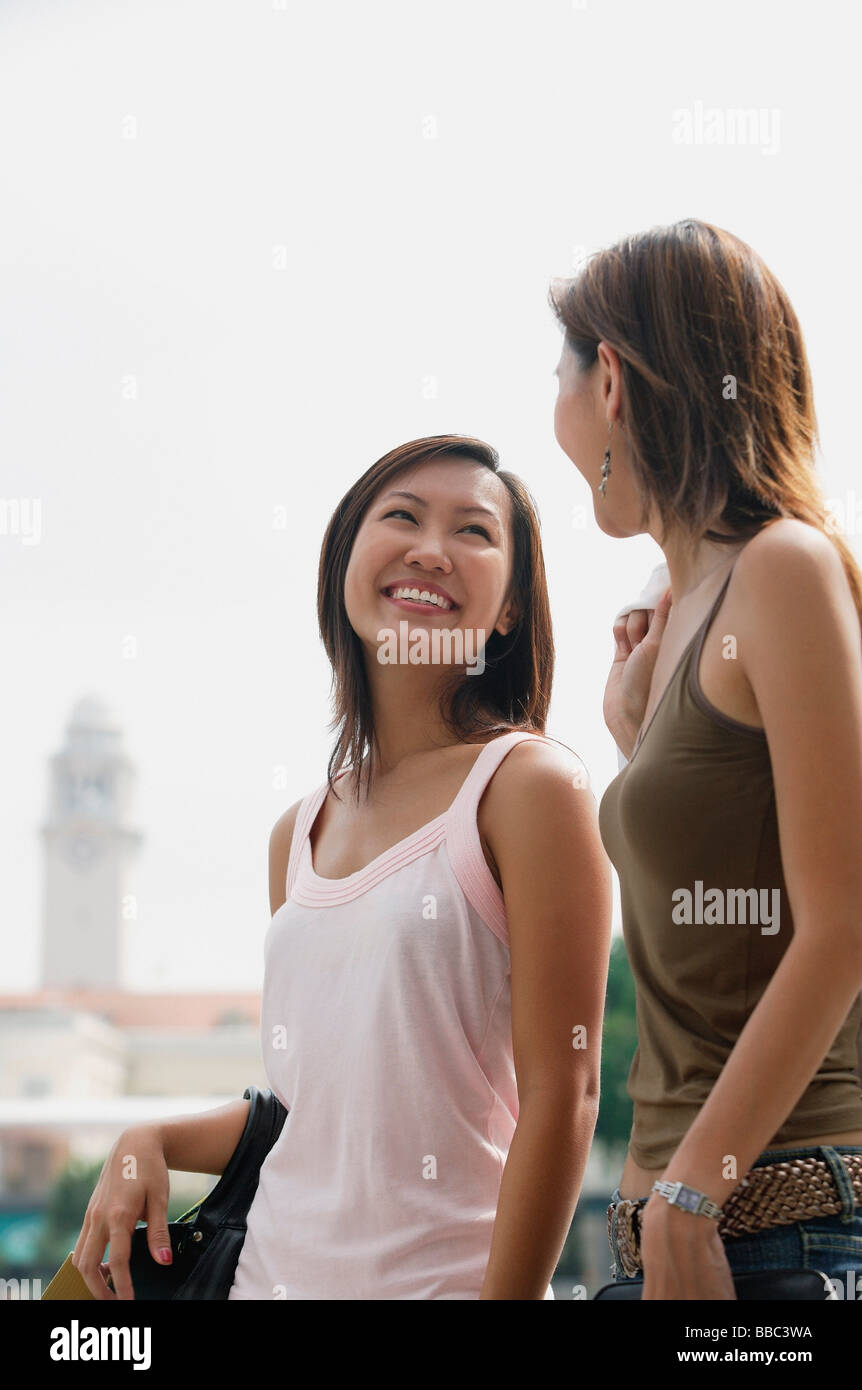 Two women walking side by side, smiling at each other Stock Photo - Alamy