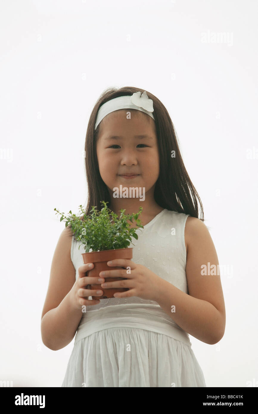 young girl holding plant, smiling, looking at camera Stock Photo - Alamy