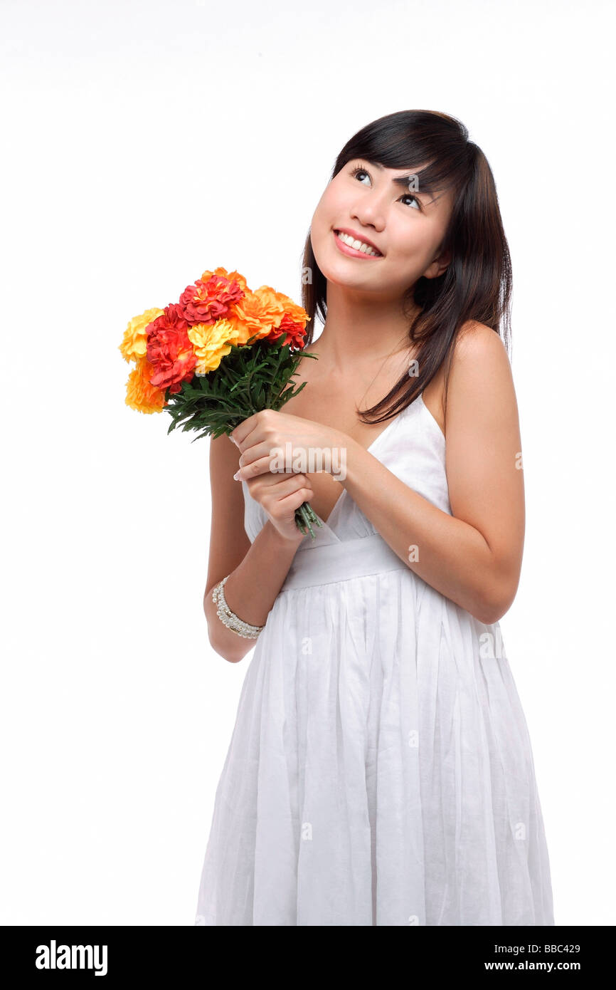 Young woman wearing white dress and holding bouquet of flowers Stock ...