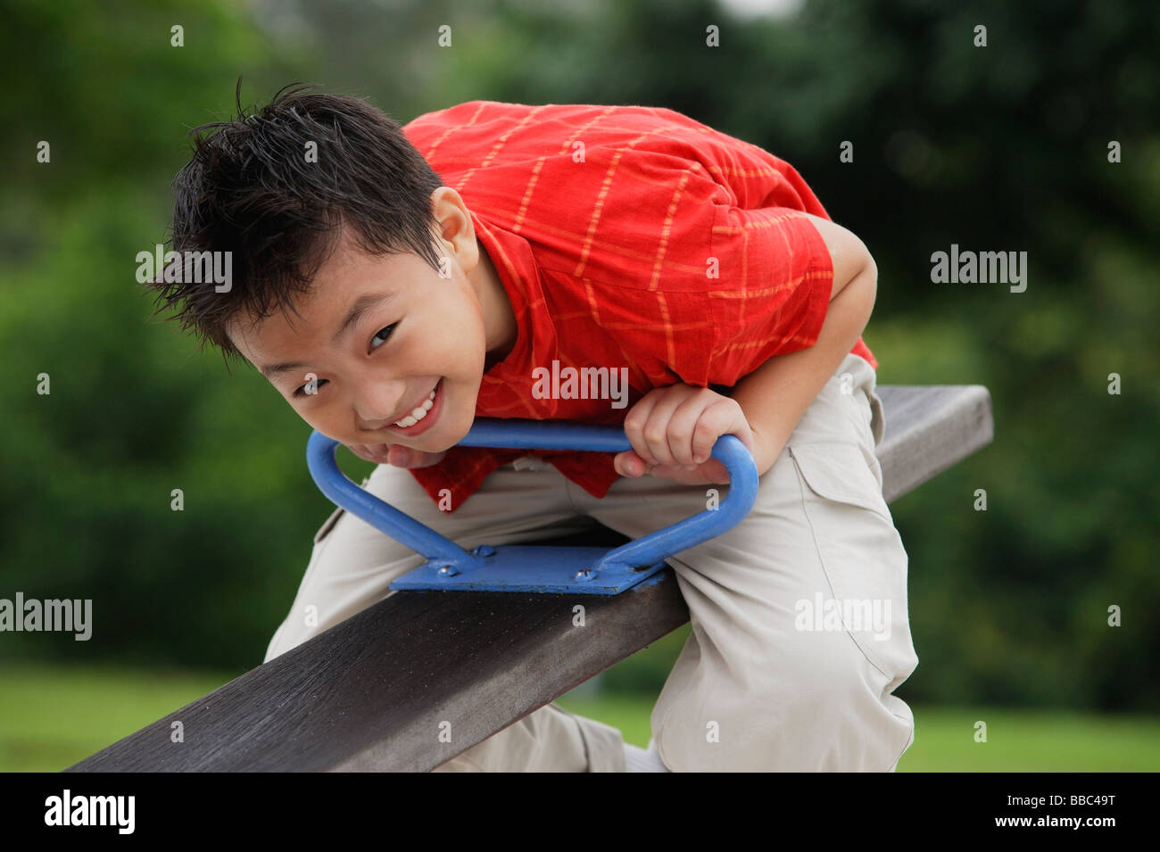 Boy sitting on See-Saw in playground Stock Photo