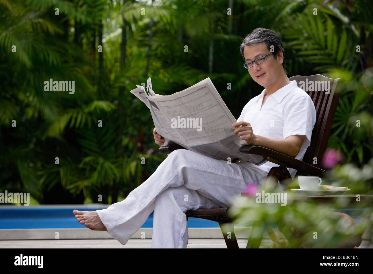 Mature man sitting outdoors, reading newspaper Stock Photo - Alamy