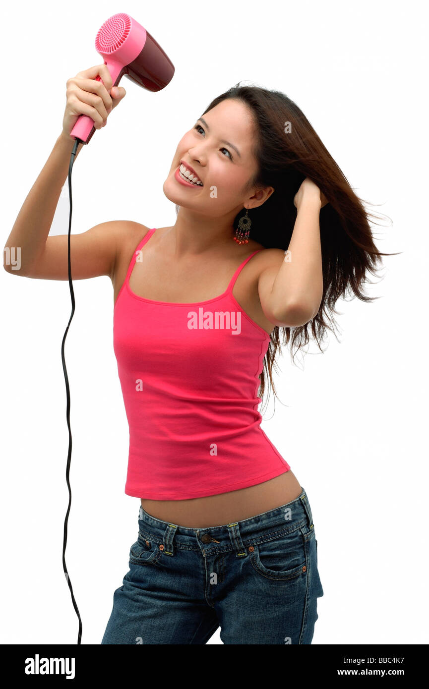 Young woman blow drying hair and smiling Stock Photo - Alamy