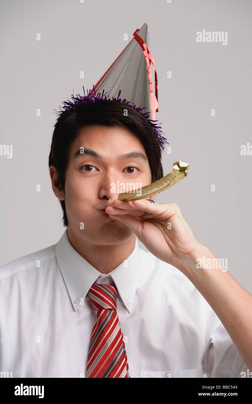 Businessman wearing party hat and using noisemaker Stock Photo Alamy