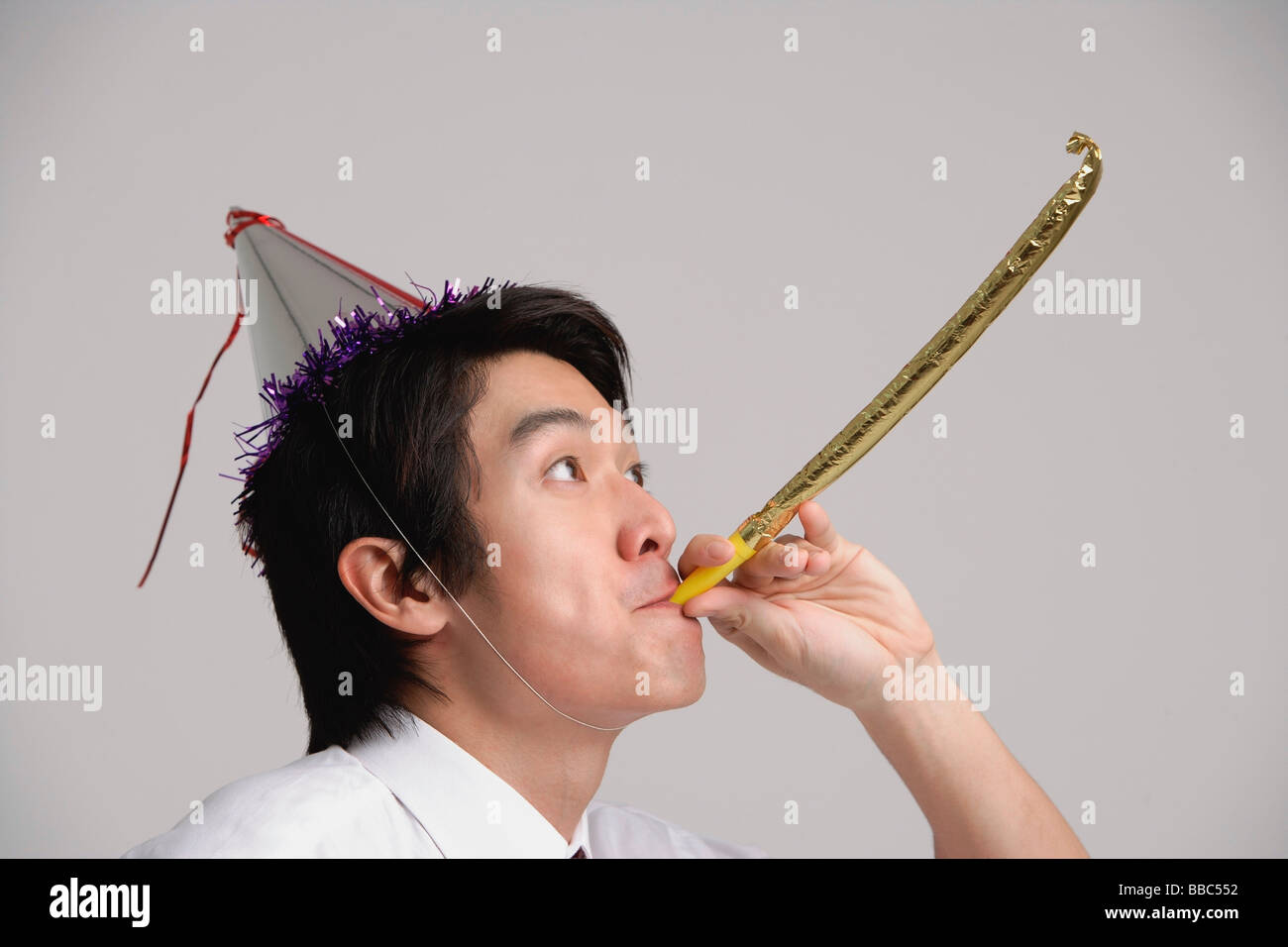 Man wearing party hat and using noisemaker Stock Photo Alamy