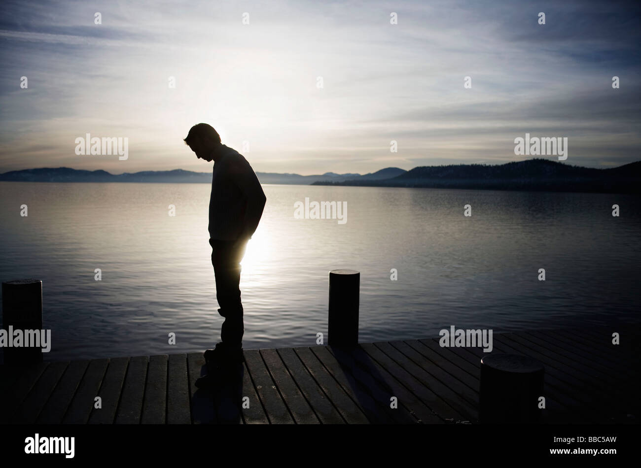 Man standing on pier at sunset Stock Photo