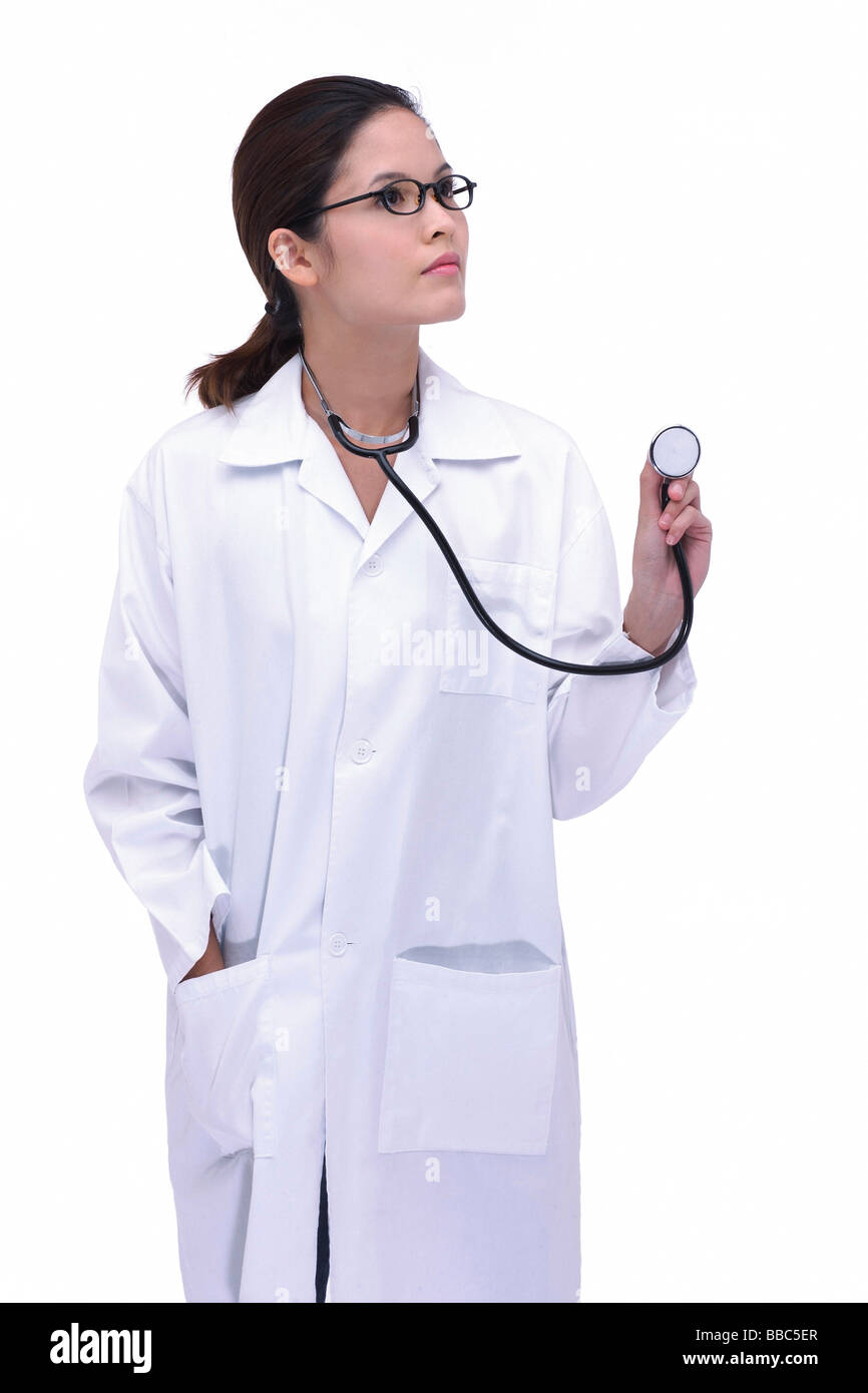 Female doctor in lab coat, holding stethoscope, looking away Stock