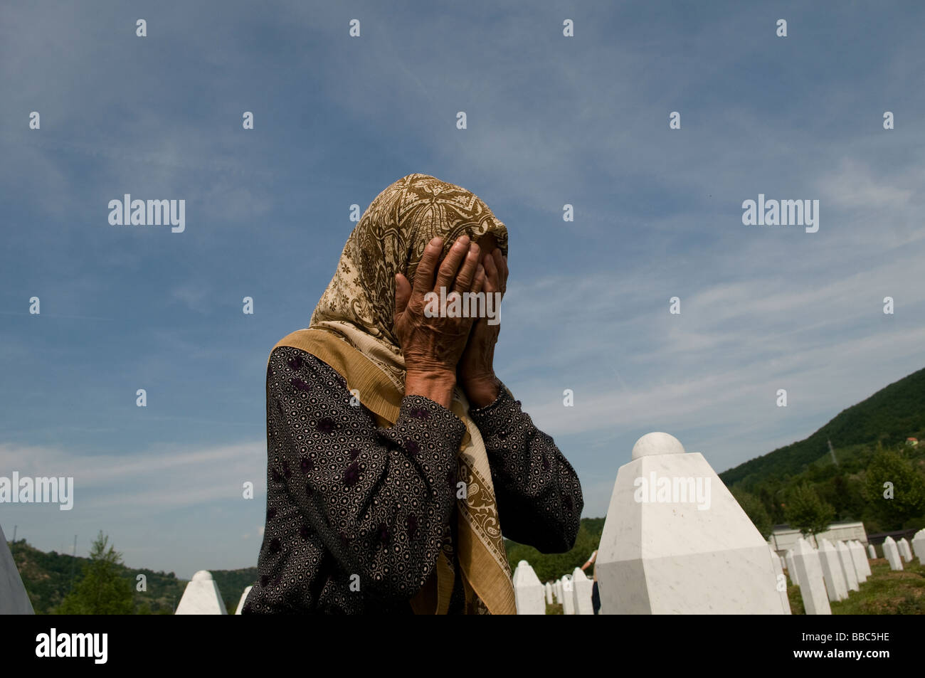 A Bosnian Muslim woman mourns between graves of her relatives, victims of the Srebrenica genocide, at the cemetery in Potocari near Srebrenica, Bosnia Stock Photo