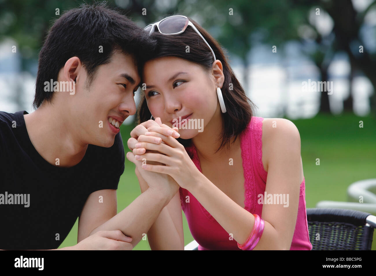 Couple sitting side by side, face to face, holding hands Stock Photo
