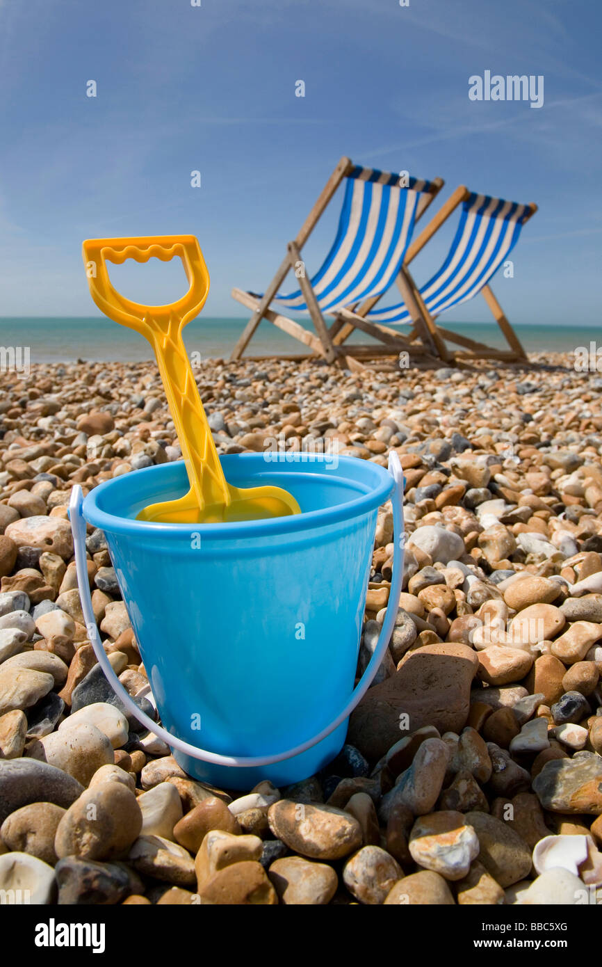 bucket and spade with deckchairs on pebble beach Stock Photo Alamy