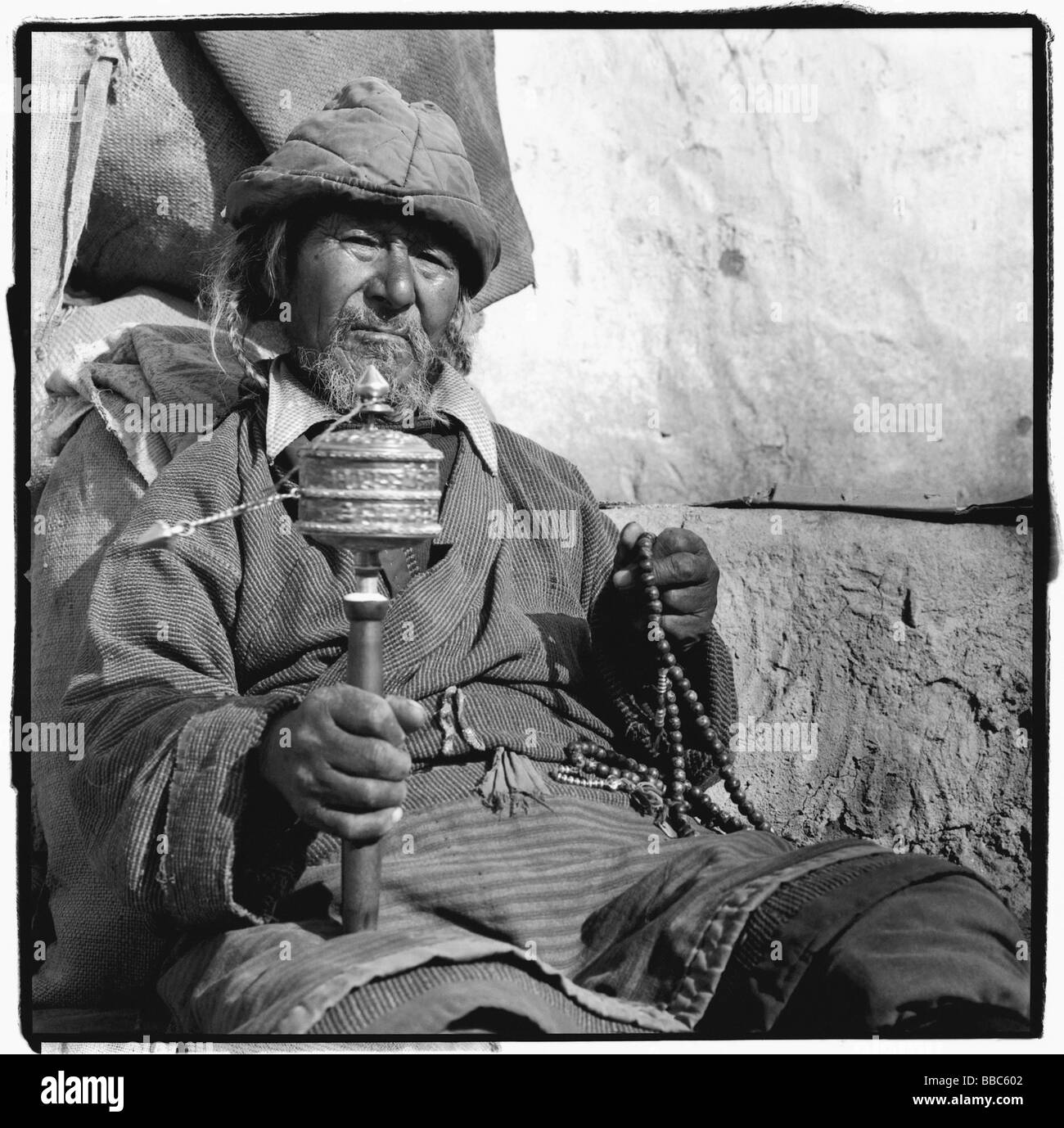 India, Ladakh, Leh, Portrait of Tibetan man holding prayer wheel and prayer beads. Stock Photo