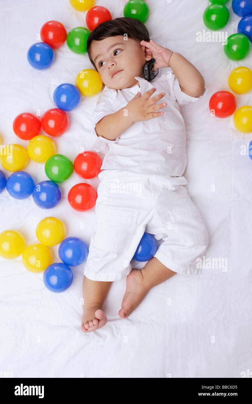 baby boy surrounded by balls, cell phone to ear Stock Photo