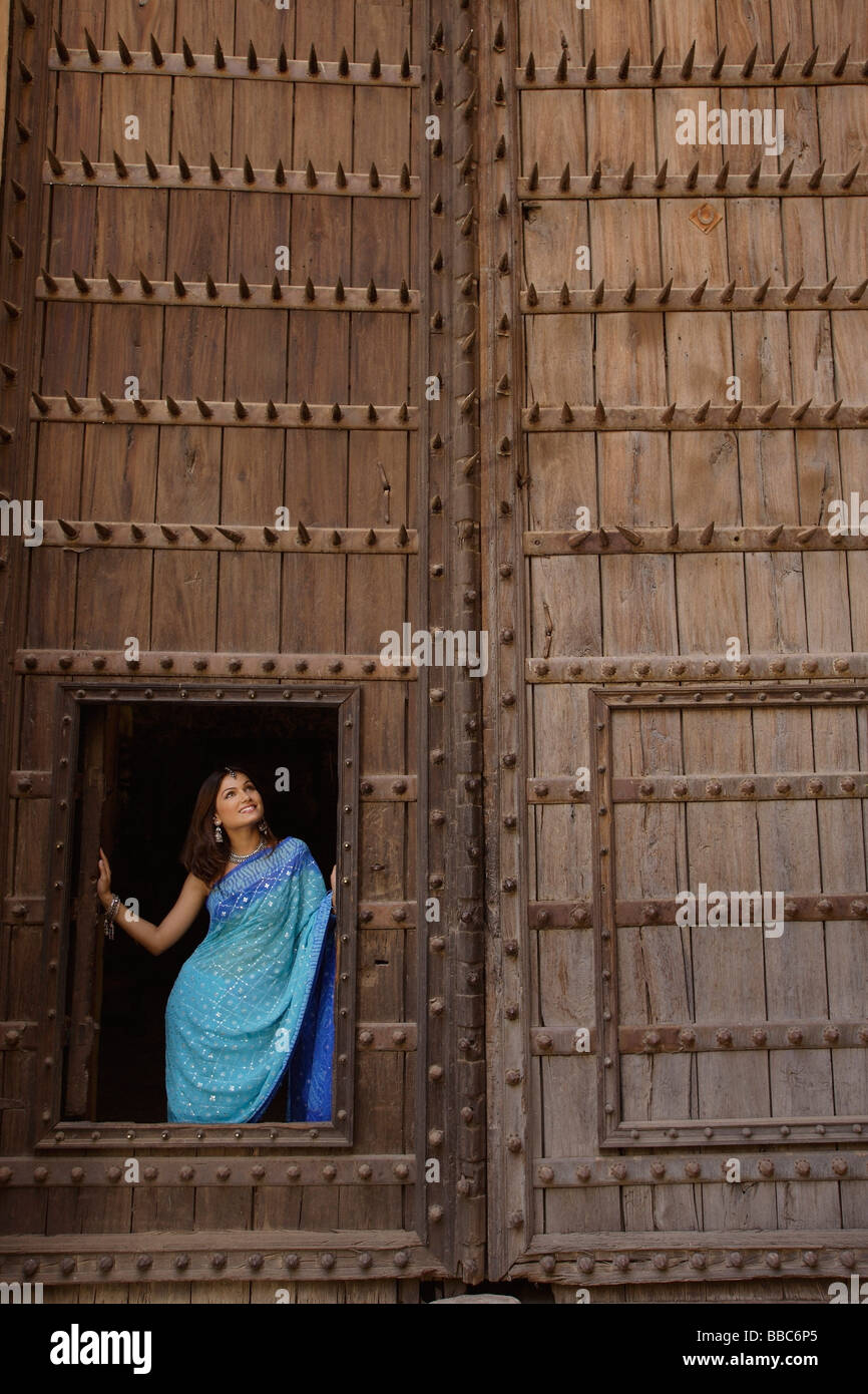 young woman standing at opening of huge wooden doorway Stock Photo - Alamy