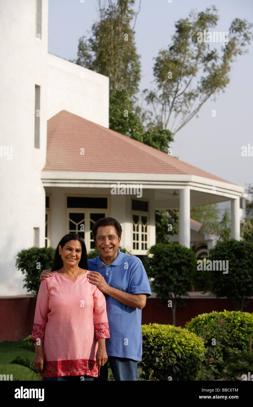 smiling couple standing in front of house Stock Photo - Alamy
