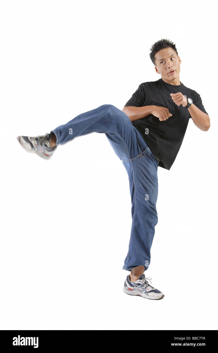 Young man standing on one leg, kicking Stock Photo