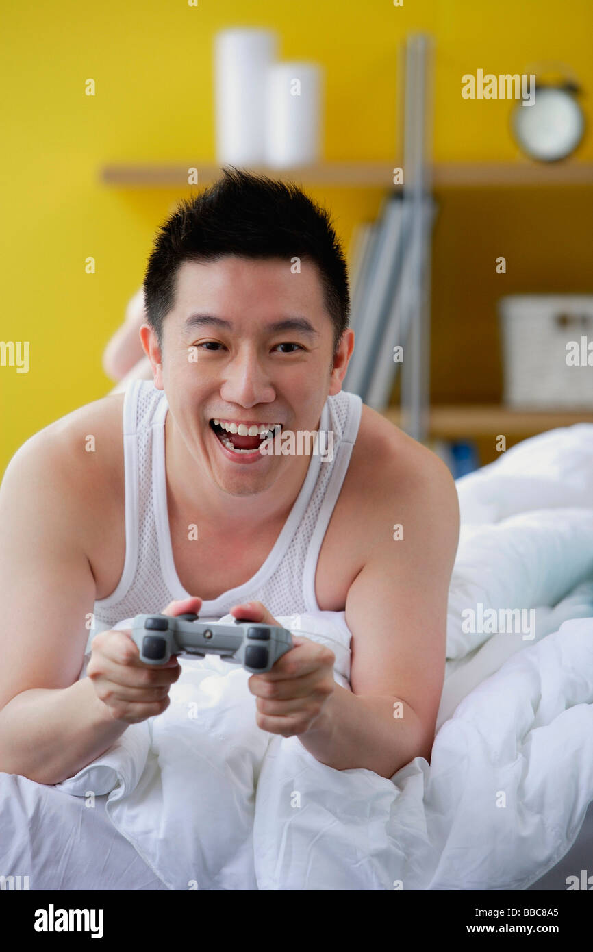 Man lying on bed, playing video game Stock Photo Alamy