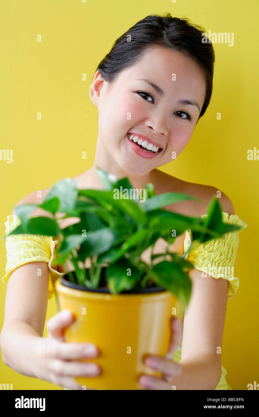 Woman holding house plant, smiling Stock Photo