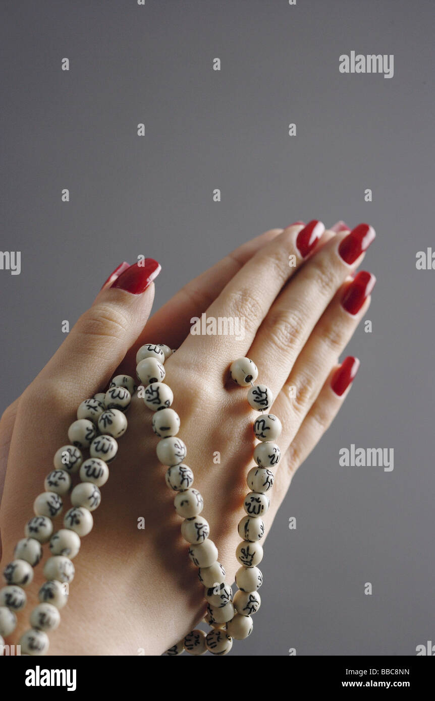 Womans hands in praying position with prayer beads Stock Photo - Alamy