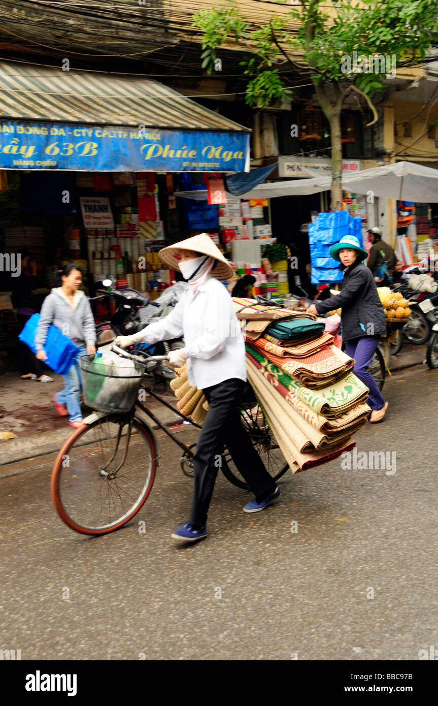 Street hawker selling matts on her bicycle in old Quarter, Hanoi, Vitenam. Stock Photo