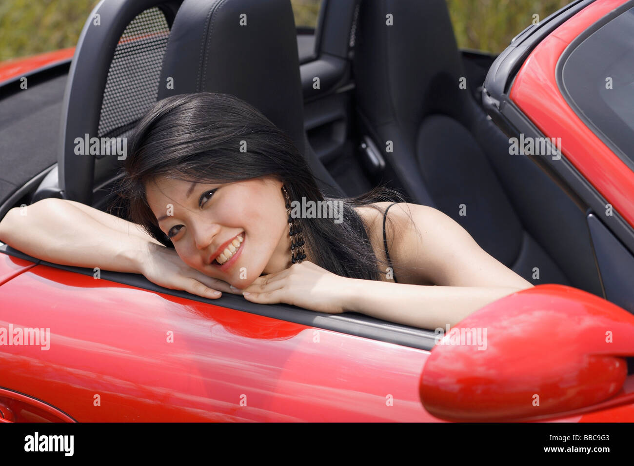 Woman sitting in red sports car, smiling at camera Stock Photo - Alamy