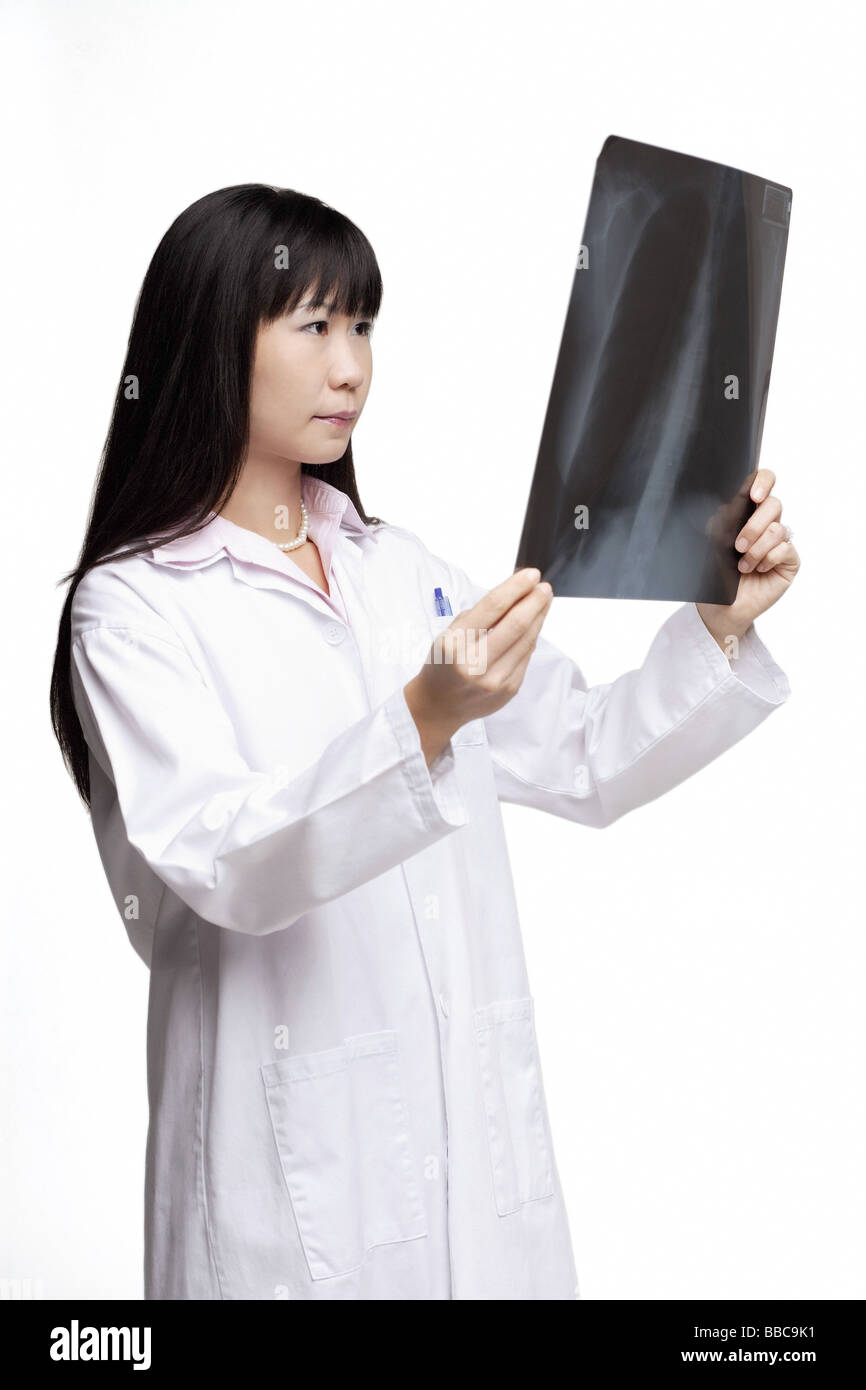 Woman in lab coat, looking at Xray Stock Photo Alamy