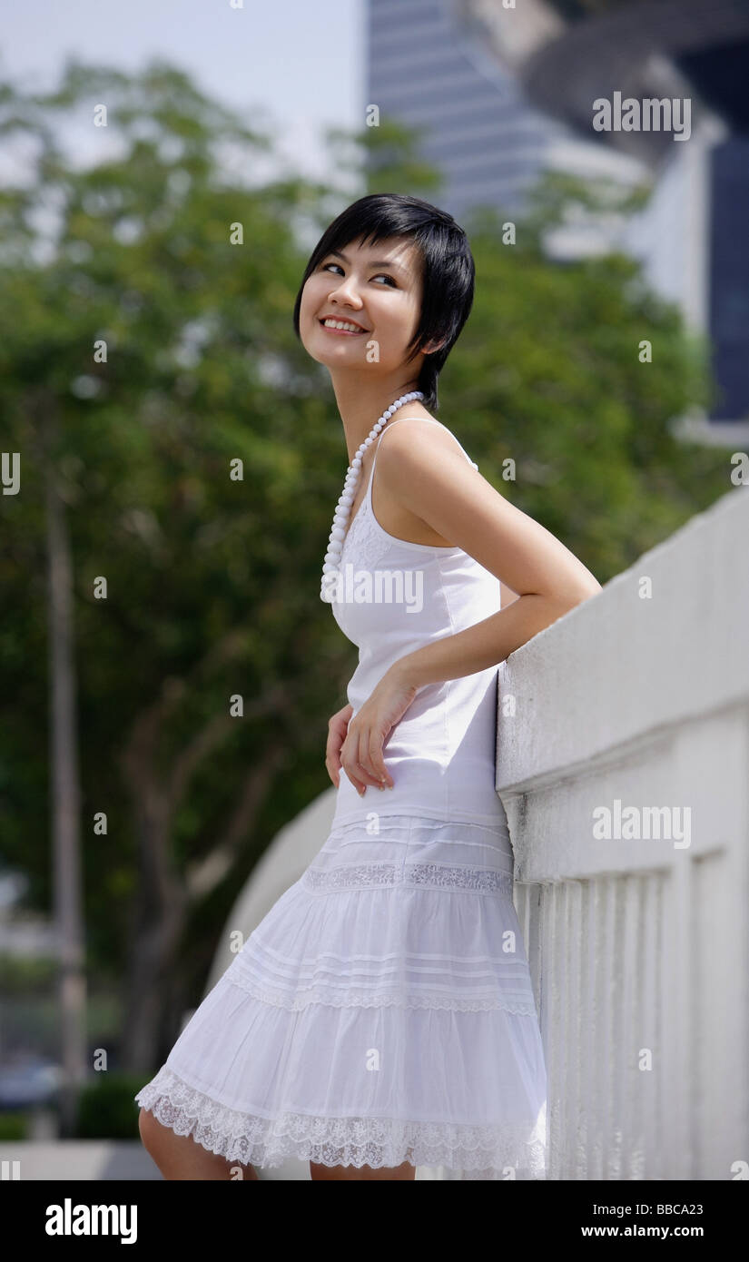 Woman dressed in white, leaning on bridge Stock Photo