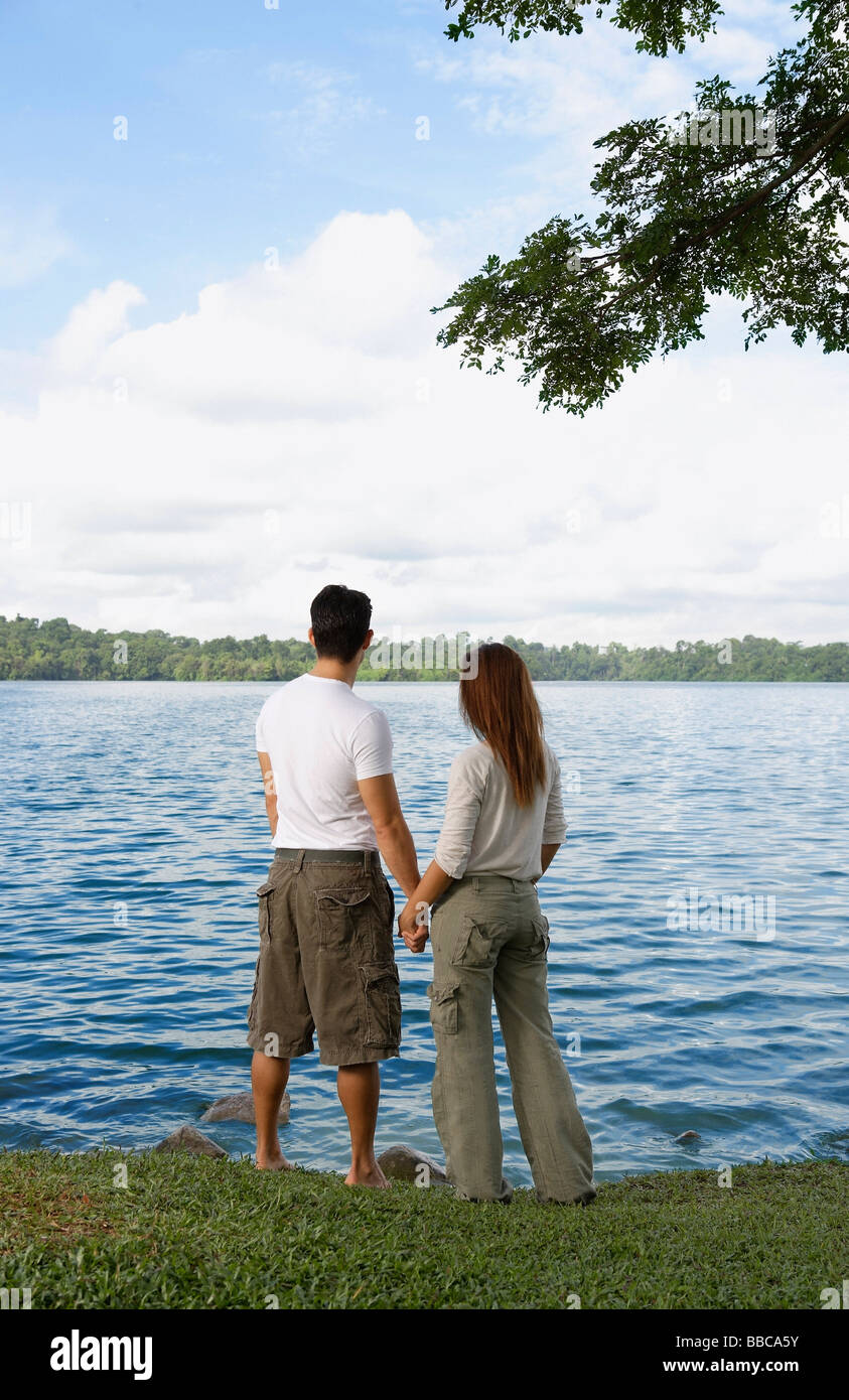 Couple holding hands looking at lake Stock Photo - Alamy