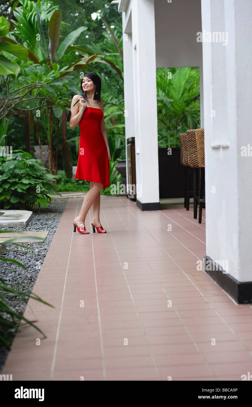 Woman in red dress, standing outside building Stock Photo