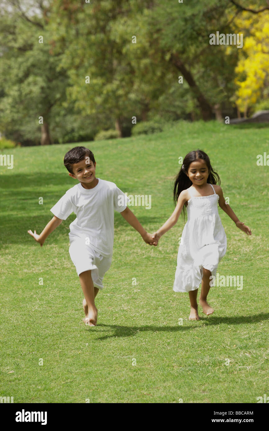 two little children running through a park holding hands Stock Photo ...