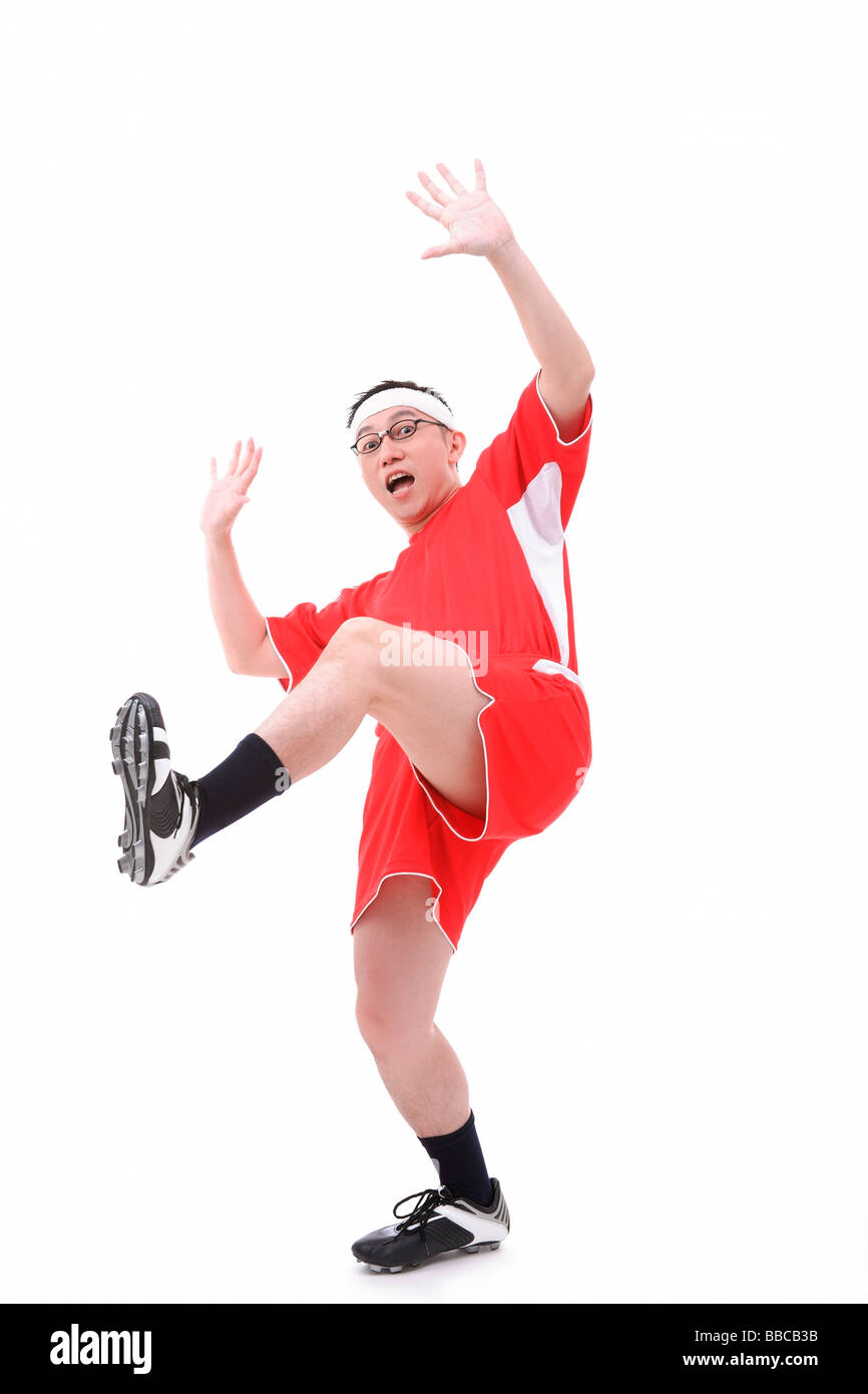 Man in soccer uniform, standing on one leg, shocked expression Stock Photo