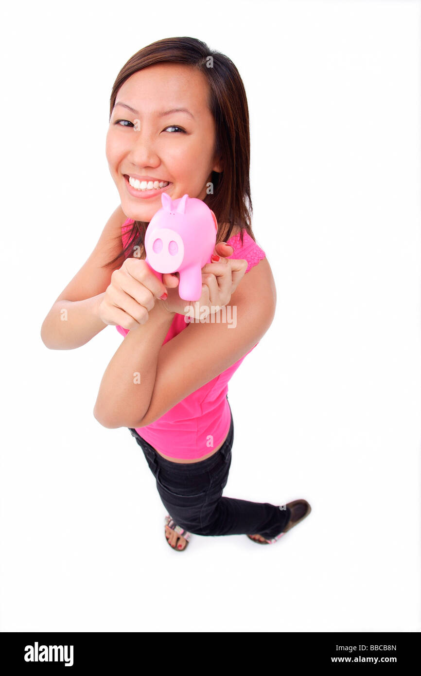Young woman holding piggy bank, smiling up at camera Stock Photo - Alamy