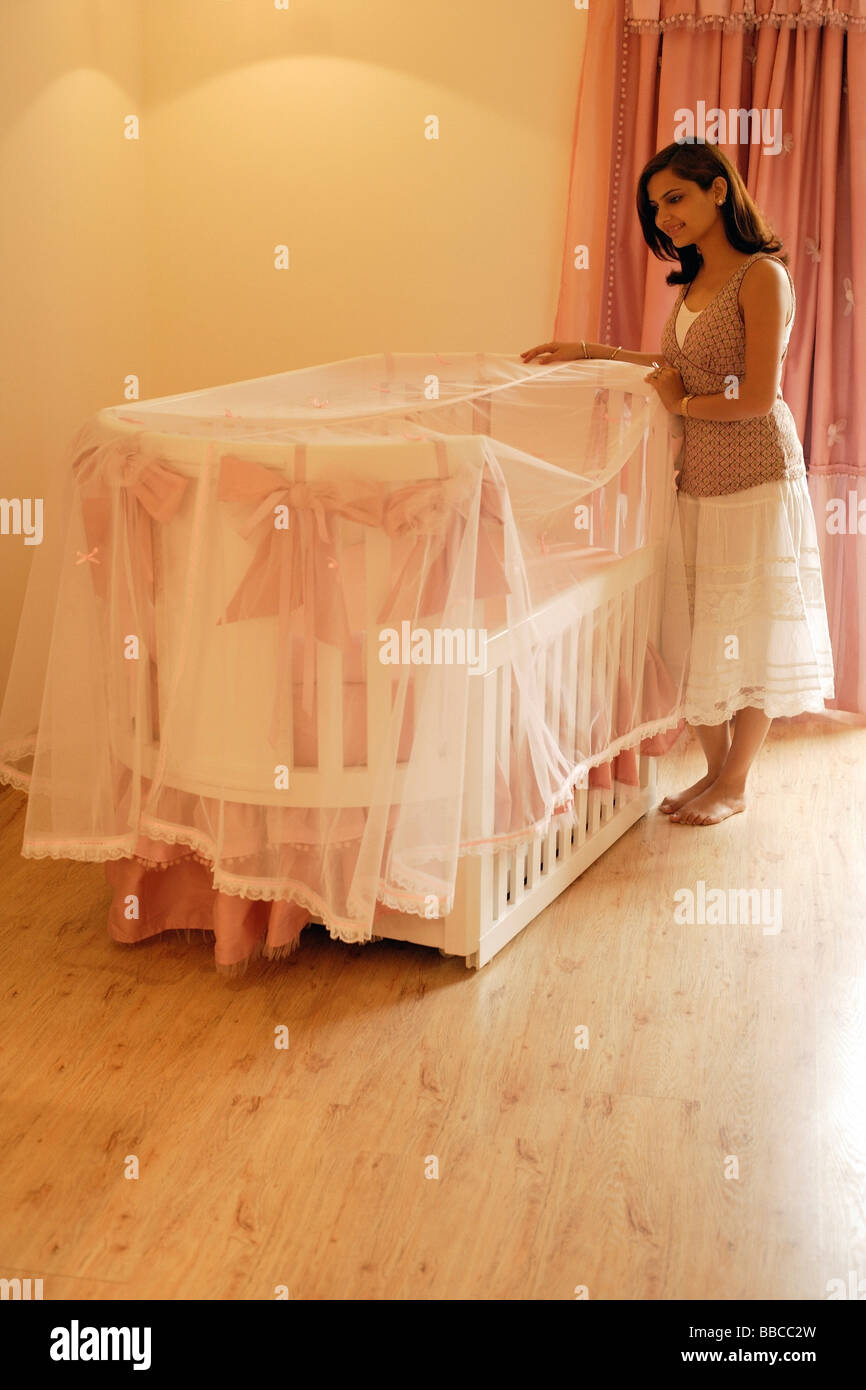 mother looking into baby crib Stock Photo Alamy
