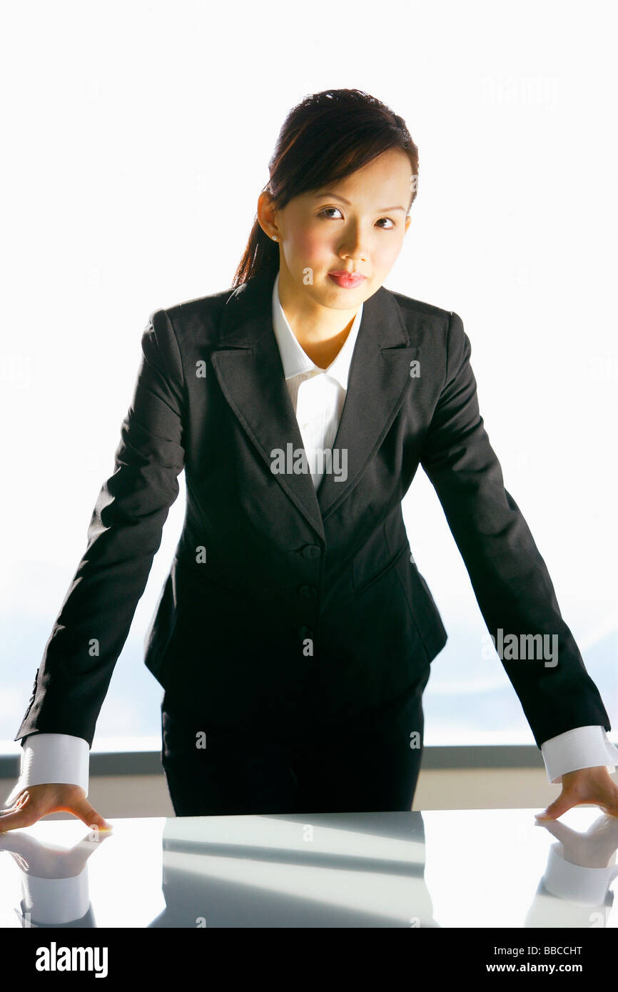 Businesswoman leaning on table, looking at camera Stock Photo